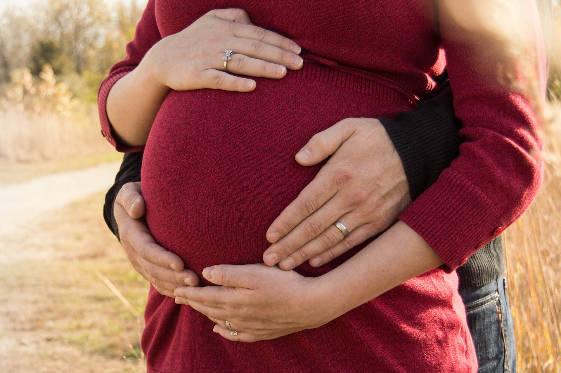 Un homme enlacant sa partenaire enceinte de dos