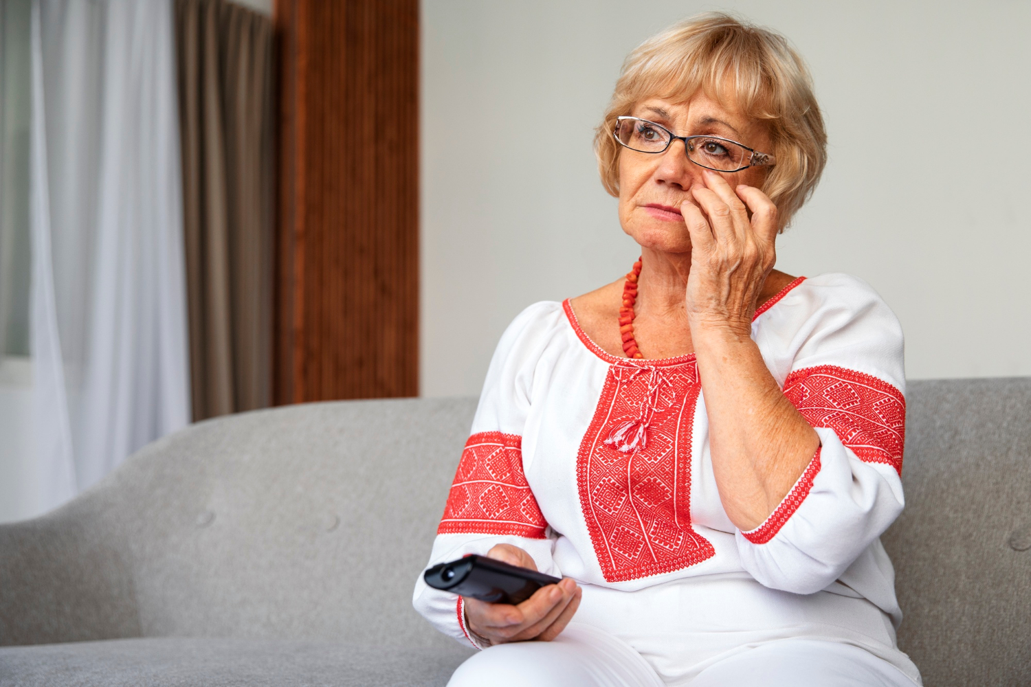 Une vieille femme triste tenant une télécommande