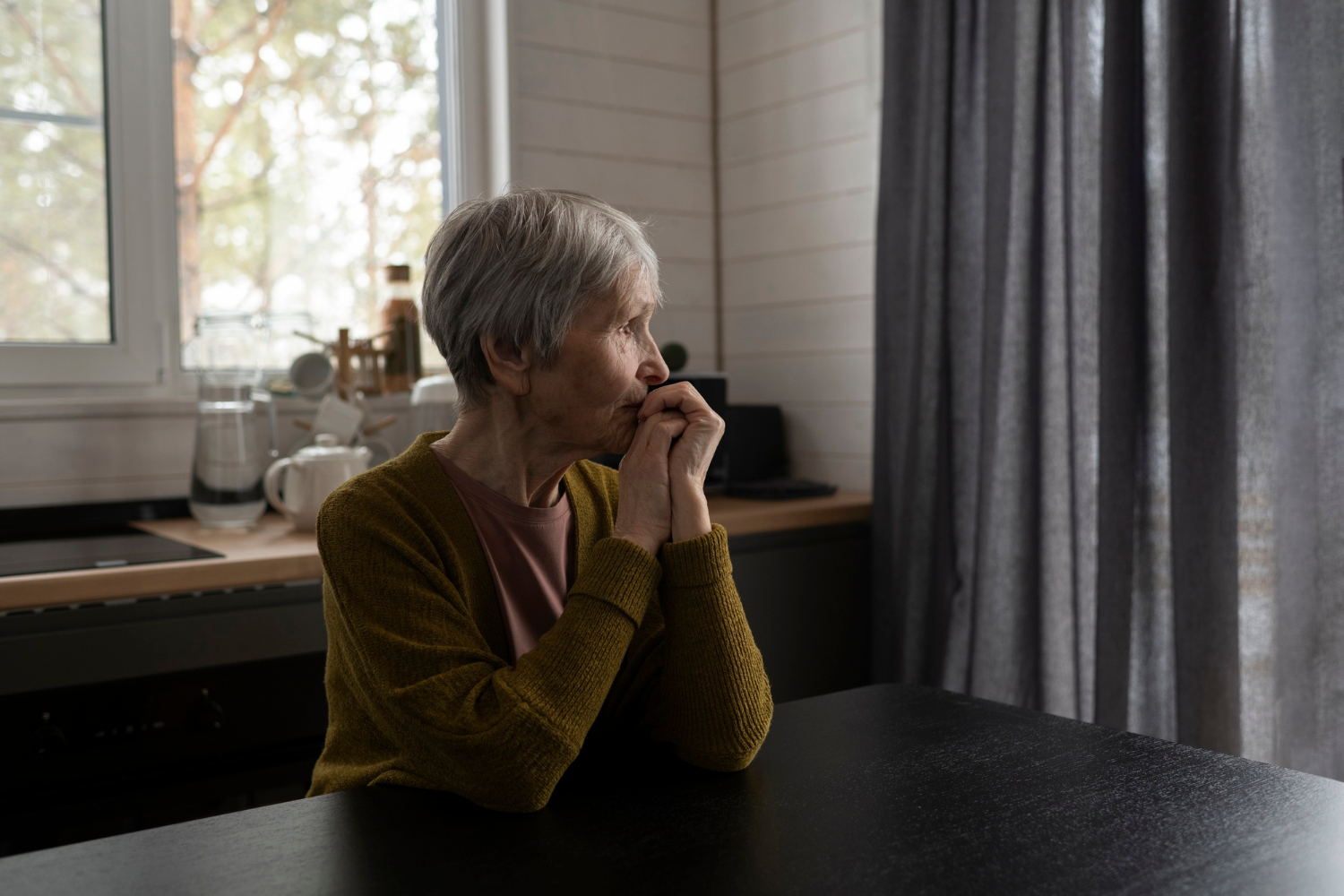 Une femme âgée pensant assise à une table